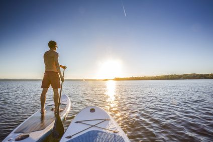 Stand-up-Paddler im Gegenlicht der untergehenden Sonne