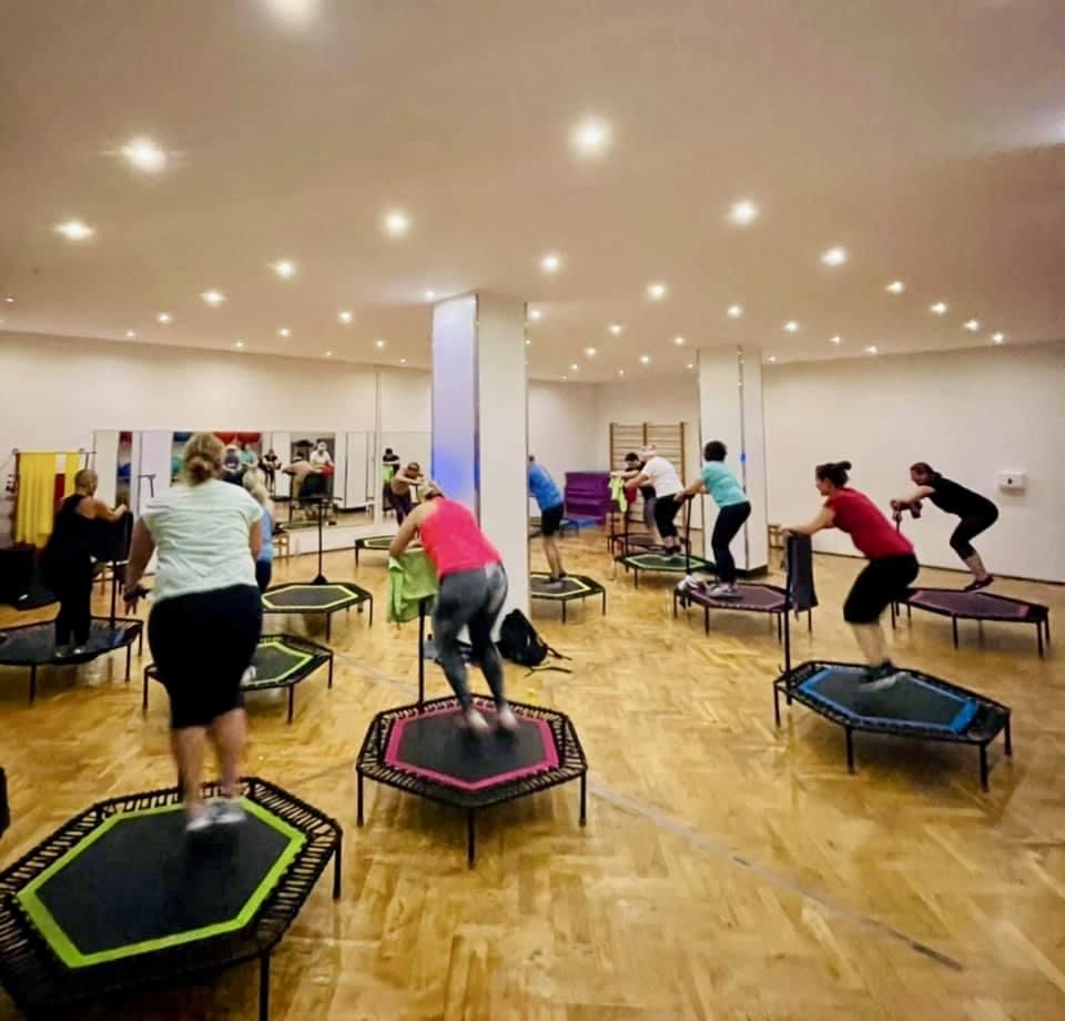 Jumping-Fitness-Kurs auf Mini-Trampolinen in einem hellen Kursraum