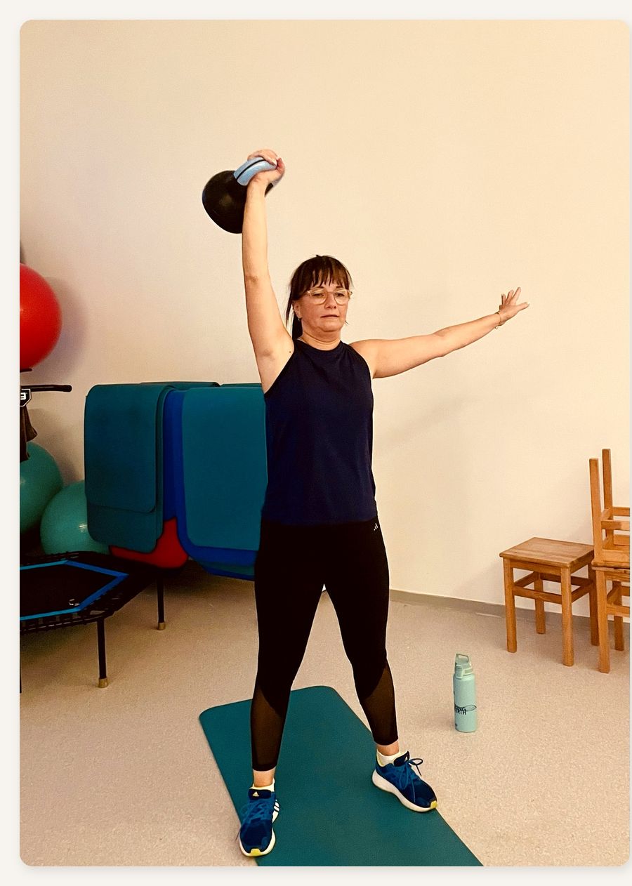Teilnehmerin stemmt eine Kettlebell über den Kopf